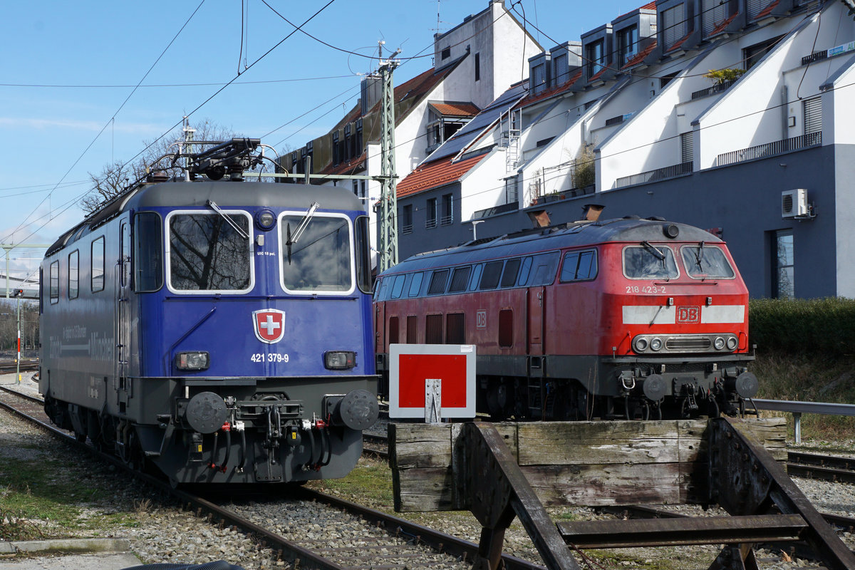 Einschränkung im Bahnverkehr wegen dem Coronavirus.
Betroffen ist auch der
EC ZÜRICH-MÜNCHEN.
Am 12. März 2020 standen die Re 421 394-8 sowie die Re 421 379-9 mit dem Werbeanstrich für die schnellere Verbindung von Zürich HB nach München im Einsatz.
Nach der Aufhebung vom Bahnersatz verkehren seit wenigen Tagen die Züge wieder bis zum Bahnhof Lindau.
Die SBB Re 421 379-9 sowie die DB BR 218 423-2 warten in Lindau gemeinsam auf den nächsten Einsatz.
Fotostandort Angestelltenparkplatz hinter den Prellböcken, Bildausschnitt Fotoshop. 
Foto: Walter Ruetsch 