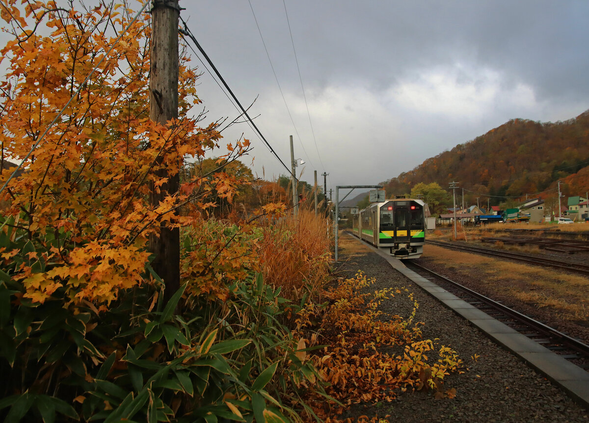 Einst war das die Hauptstrecke nach Sapporo, zur Hauptstadt von Hokkaidô. Jetzt fahren die Züge mit hoher Geschwindigkeit den flachen Umweg über die Muroran-Hauptlinie. Auf der alten Bergstrecke (im Bild) verbleibt nur noch ein spärlicher Lokalverkehr, und dieser wird auch bald eingestellt und die Strecke stillgelegt. Der Grund: Der Shinkansen-Hochgeschwindigkeitszug wird bald von seinem jetzigen Endpunkt oberhalb der Stadt Hakodate nach Sapporo weitergeführt (wohl fast ganz im Tunnel). Bild: Die zwei Triebwagen H100-5 und H100-12 in Shikaribetsu, 29.Oktober 2022. In solchen kleinen Stationen wie hier liegen oft Gästebücher bereit, aus denen man die interessantesten persönlichen Erlebnisse ersehen kann, zunächst einmal wie überhaupt jemand auf die Idee kommt, diesen entlegenen Bahnhof aufzusuchen, oder wie Leute einfach mal eine Reise ins  Nichts  machen wollen und sich hier eintragen.  