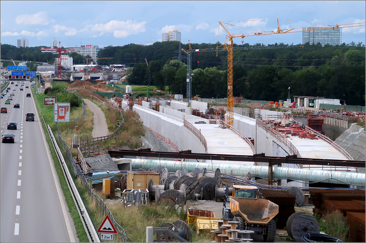 Eisenbahnbau auf der Filderebene -

Blick auf die die Neubaustrecke neben der Autobahn A8 beim Flughafen. Im Vordergrund sind die beiden abzweigenden Tunnelröhren sichtbar, die zum Flughafen-Fernbahnhof führen werden. Diese Röhren sind ab hier unter der Autobahn und unter der Messe bis zum zukünftigen Bahnhof schon bergmännisch aufgefahren.
Im Hintergrund ist zudem das Portal zum Fildertunnel erkennbar. Dort kommen die Züge nach einer langen ansteigenden Fahrt im Tunnel wieder ans Tageslicht.

08.08.2021 (M)