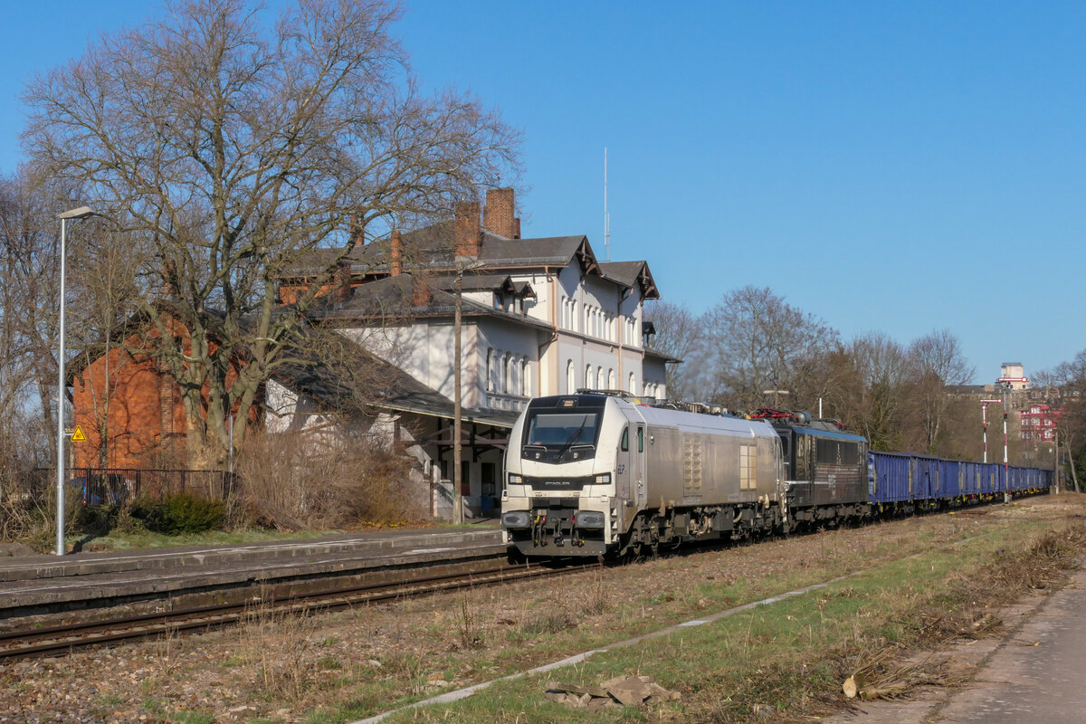 ELP/EBS 159 206 führte am 30.03.2021 diesen Zug, bestehend aus EBS 155 007 und einer Leine E-Wagen für die Holzverladung Sonneberg, bis Saalfeld an. Im Hintergrund das markante Bahnhofsgebäude Pößneck oberer Bahnhof.
