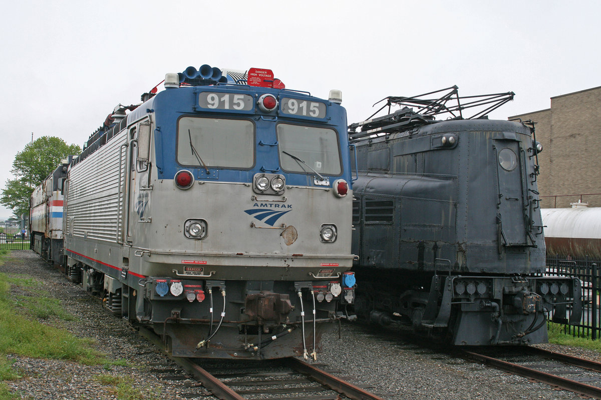 EMD AEM-7 Nr. 915 der Amtrak. Ausgestellt im Railroad Museum of Pennsylvania in Strasburg, Pennsylvania / USA, 17. Mai 2018. Rechts daneben eine GG-1 der Pennsylvania Railroad ohne Nummer.