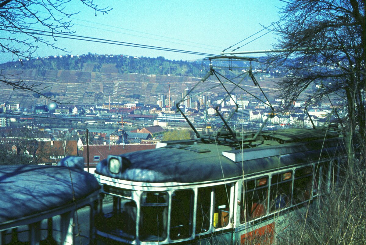 END Straßenbahn Esslingen-Nellingen-Denkendorf__Die aber auch nach Scharnhausen und Neuhausen fuhr.__Neubau-Zug unterhalb der Ausweichhaltestelle 'Zollberg'. Im Tal das Bahnhofsgelände, darüber die Weinberge.__04-03-1976 