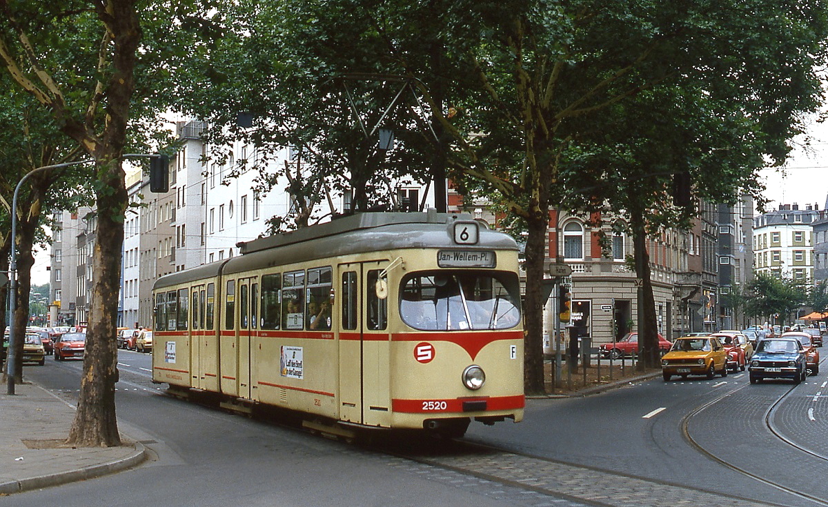 Ende der 1970er Jahre fährt der GT6 2520 als Umleiter der Linie 6 über die zu diesem Zeitpunkt nur als Betriebsstrecke genutzte Verbindung durch die Bachstraße in Richtung Bilker Allee, rechts die Gleise der Linie 708. Dieser Streckenabschnitt wird heute planmäßig von der Linie 707 befahren (allerdings nur noch bis zur Inbetriebnahme der Ost-West-U-Bahn im Februar 2016). Ab dem 01.06.1980 wurden mit der Gründung des Verkehrsverbundes Rhein-Ruhr dreistellige Liniennummern eingeführt, aus der 6 wurde die 706. Das weiße S auf rotem Grund weist auf den schaffnerlosen Betrieb hin, der einige Jahre zuvor eingeführt worden war.