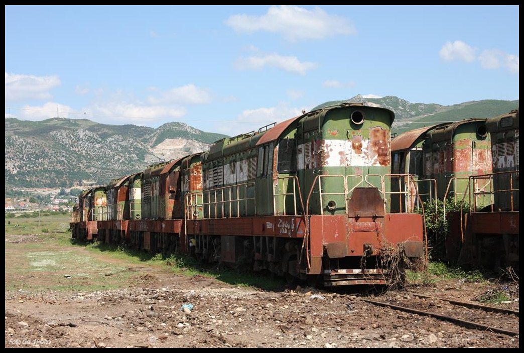 Ende des Fahrbetriebs im Bahnhof Prrenjas in Albanien nahe der mazedonischen Grenze. Ca. 15 Cmellaks und die V 2003 ex V 200124 stehen dort im Freien und rosten vor sich hin. Die Aufnahme machte ich am 18.5.2017. Im Vordergrund könnte es sich um T 6991031 handeln?!