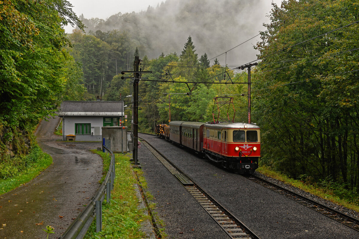 Ende September 2021 fanden auf Initiative eines Berliner Reiseveranstalters einige Sonderfahrten mit einer in den Zustand der 1970er Jahre gebrachten Garnitur auf der Bergstrecke der Mariazellerbahn statt. Die E14 der NÖVOG hatte zu diesem Zwecke das Flügelrad und die Nummerierung 1099.14 erhalten. Bei den Personenwagen wurden die Ötscherbär-Logos entfernt und es wurden auch mit Holz beladene Flachwagen mitgeführt. Leider spielte das Wetter wie bei den vergangenen Fahrten größtenteils nicht mit. Beim Kreuzungsaufenthalt im Bahnhof Puchenstuben konnte ich den Zug in einer typischen Herbststimmung dokumentieren (27. September 2021).