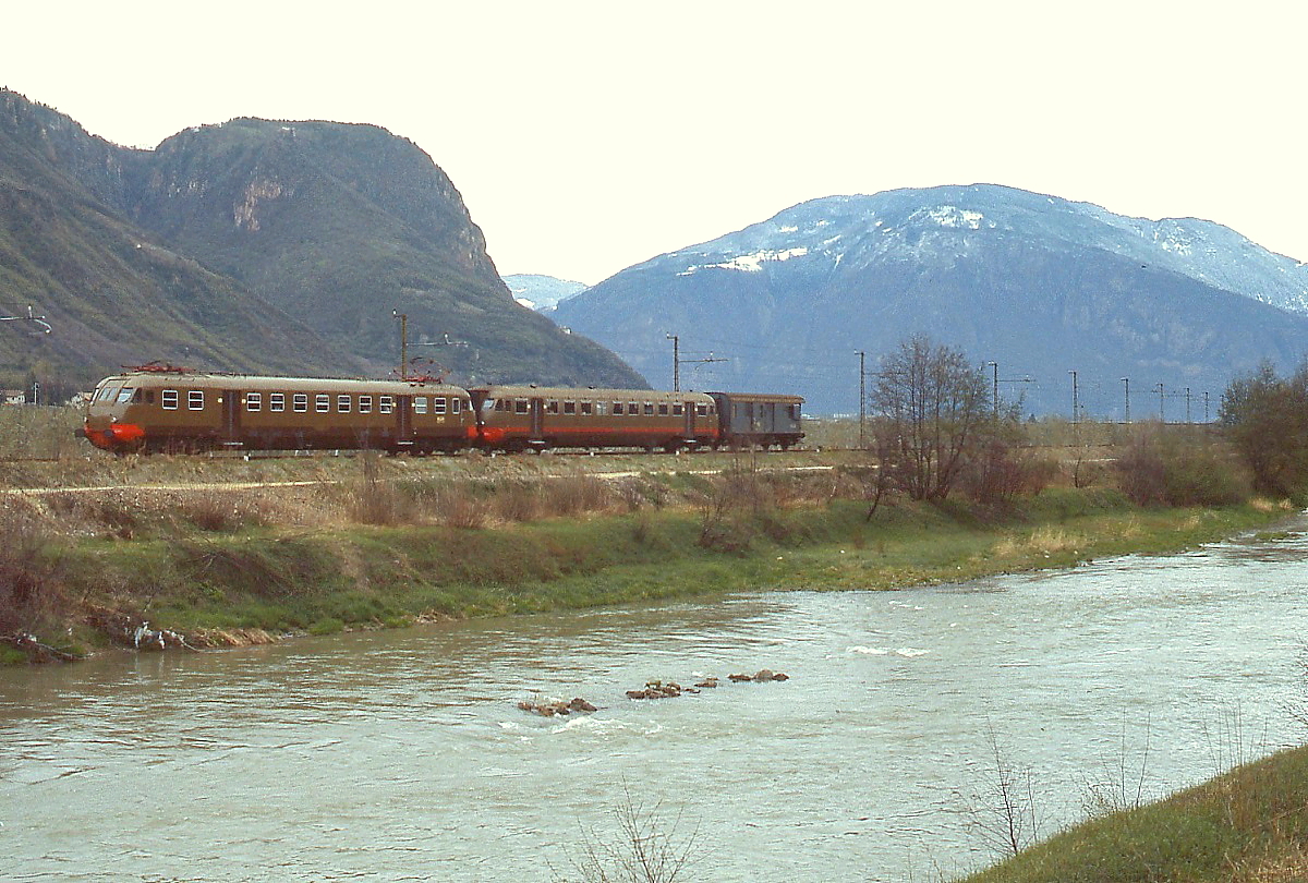 Entlang der Adige/Etsch fährt ein ALe 840 mit angehängtem Beiwagen Le 840 und einem Postwagen (?) im März 1985 von Bolzano/Bozen nach Merano/Meran