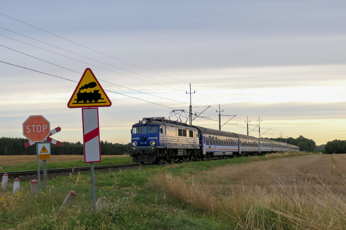 EP07-385 beförderte am Abend des 06.08.2021 einen TLK nach Krakow Glowny. Hier passierte sie einen der unzähligen unbeschrankten Bahnübergänge zu Sianozety.