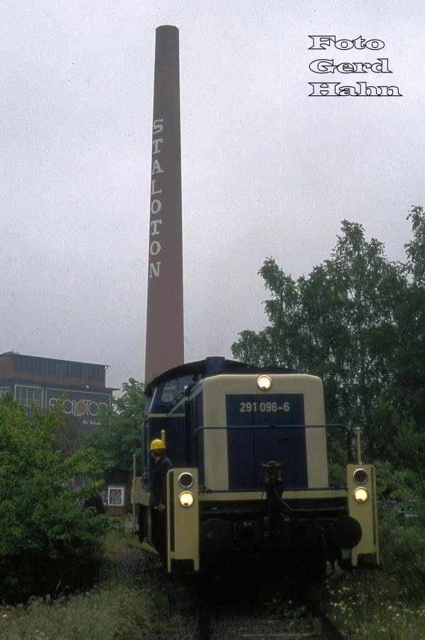 Es war einmal! - Am 7.6.1988 bediente 291096 morgens um 7.35 Uhr die Staloton Werke im Industriegebiet Westerkappeln - Velpe.
Heute ist der Schlot mit dem markanten Schriftzug abgetragen. Die Gleise im Werk sind zugestellt. Der Abzweig vom Bahnhof Velpe aus ist mehr oder minder zugewachsen. Es gibt schon seit vielen Jahren keinen Zugverkehr mehr auf diesem Anschlussgleis.