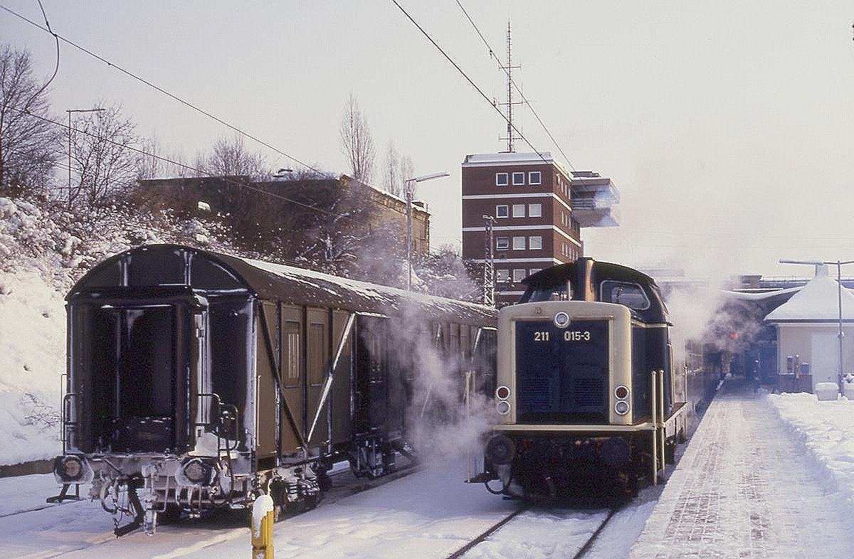 Es waren harte Wintertage im Jahr 1987. Am 13.1.1987 sieht man das deutlich am Rollmaterial der Bundesbahn im Hauptbahnhof Osnabrück. Neben dem Behelfspackwagen steht um 13.31 Uhr abfahrbereit 211015 mit dem Nahverkehrszug nach Bramsche.