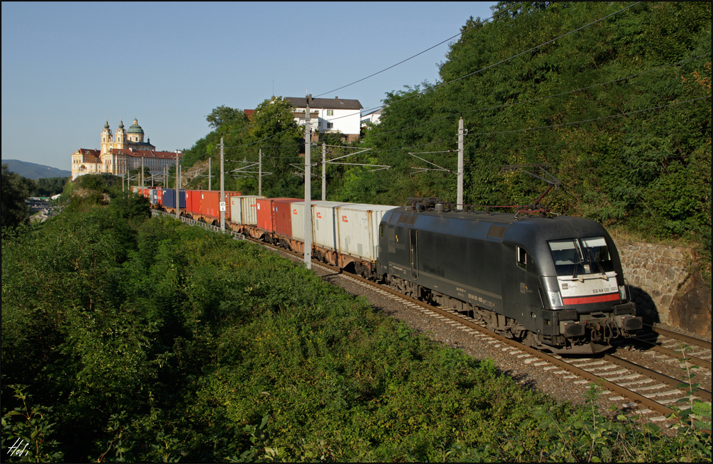 ES64U2-033 fährt am 27.08.15 mit einem Containerzug die Westbahn bei Melk entlang.
Im Hintergrund das Benediktinerkloster Stift Melk.