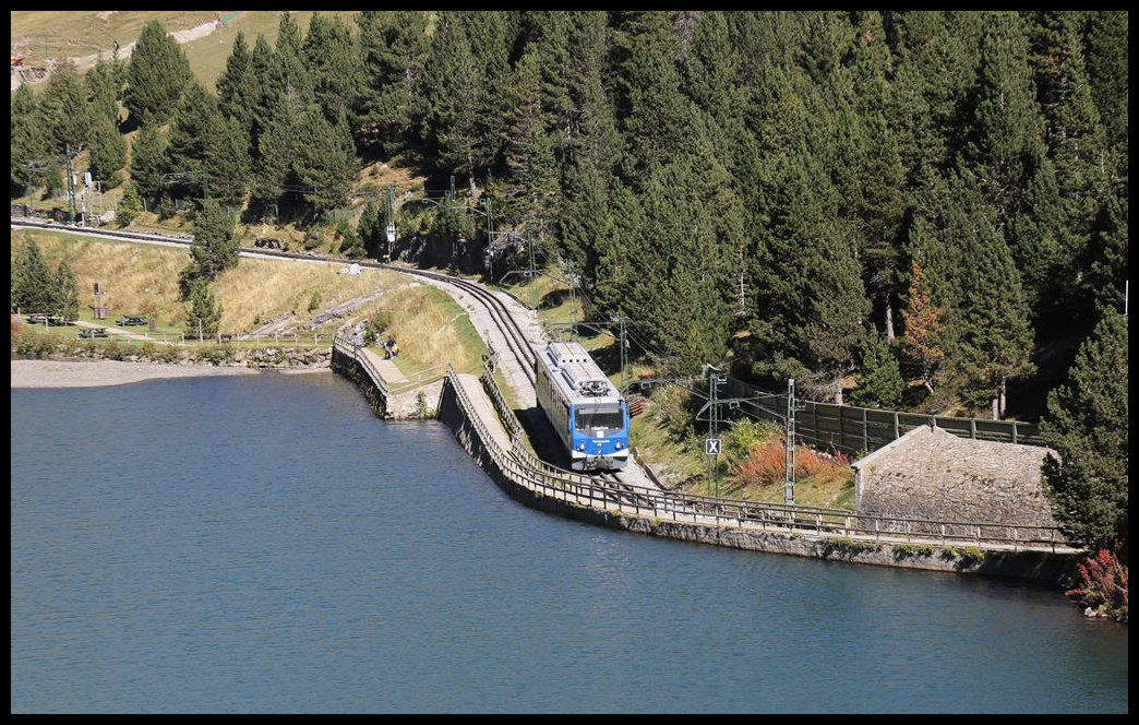 ET 6 verlässt hier am 11.10.2019 den Bergbahnhof Núria und fährt am dortigen Stausee talwärts. Am rechten Bildrand ist der erste Tunnel erkennbar, kurz vor dem sich der Triebwagen befindet. 