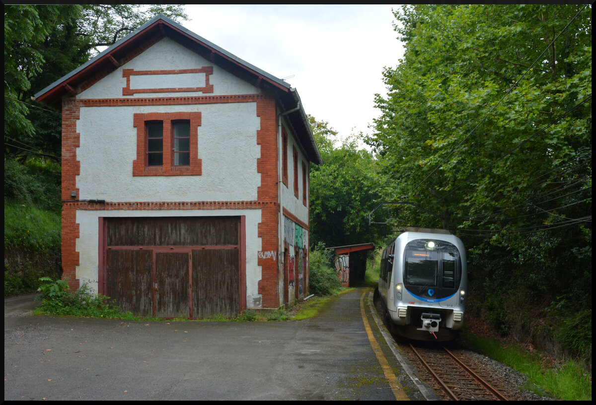 Euskotren Trena: Im ehem. Bf. Txokoalde halten schon lange keine Züge mehr. Ein CAF-Triebzug der BR 900 durchfährt die verlassene Station pünktlich in Richtung San Sebastian (baskisch: Donostia). 16.08.2023