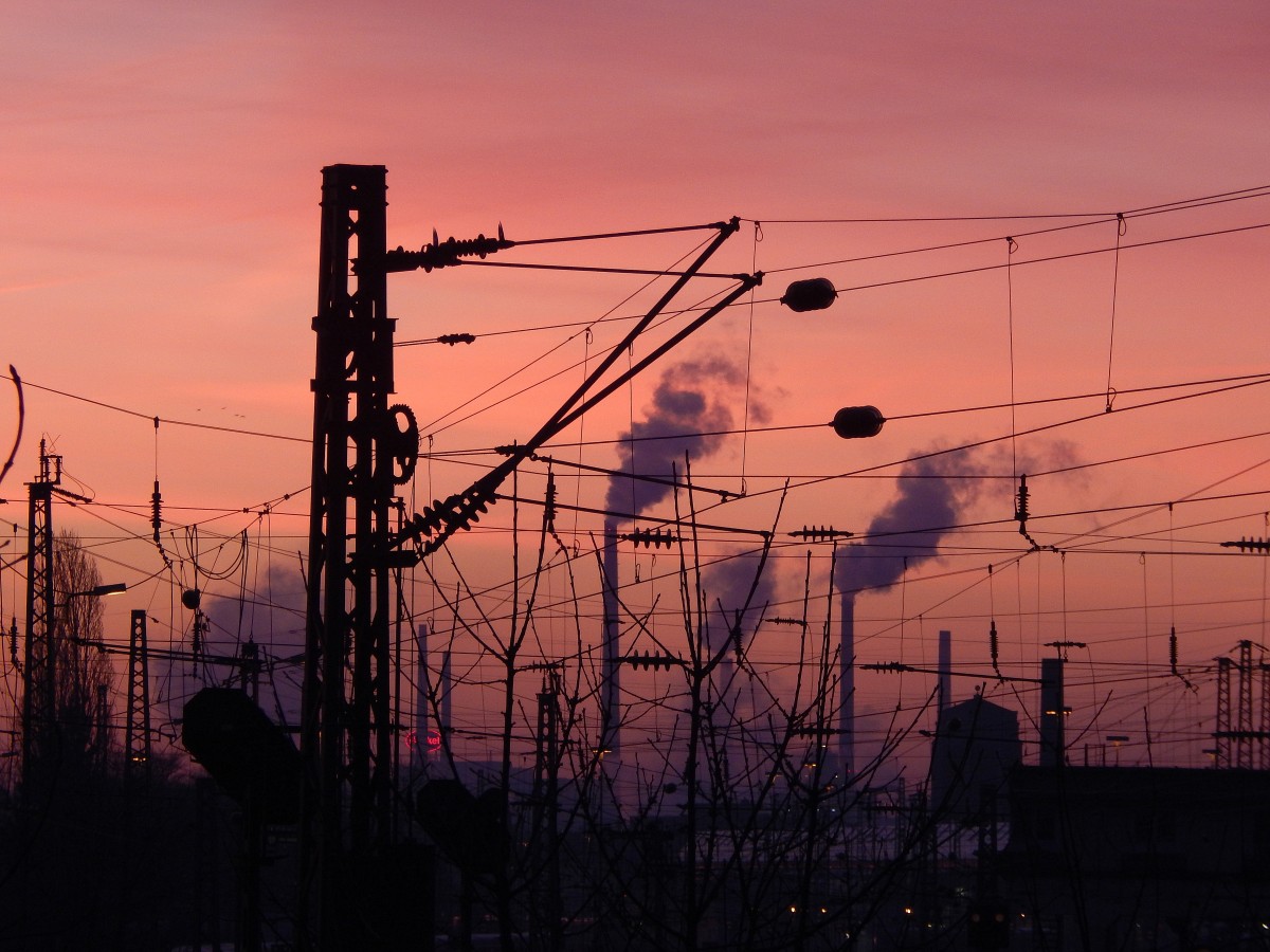 Fahrdraht Halter mit Masten im noch tief rot/orangen Morgenhimmel des 6.1.15
Im Hintergrund sind die hohen Schlote der Fabriken um Düsseldorf zu sehen.

Oberbilk 06.01.2015