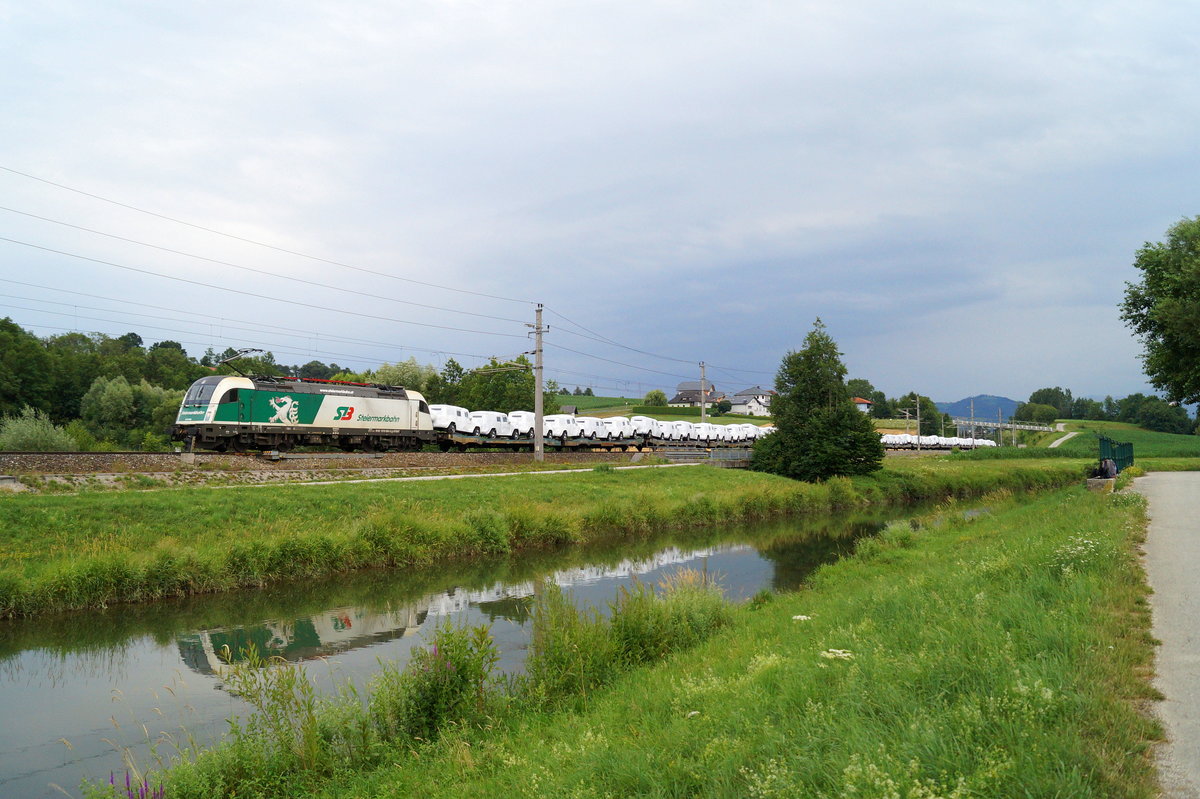 Farblich zur sommerlichen Idylle sehr passend zeigt sich die 1216 960 der Steiermarkbahn am 08.07.2019 mit hochwertiger Fracht am Haken: Bei Wartberg an der Krems befördert sie Fahrzeuge der Mercedes G-Klasse in Richtung Linz.