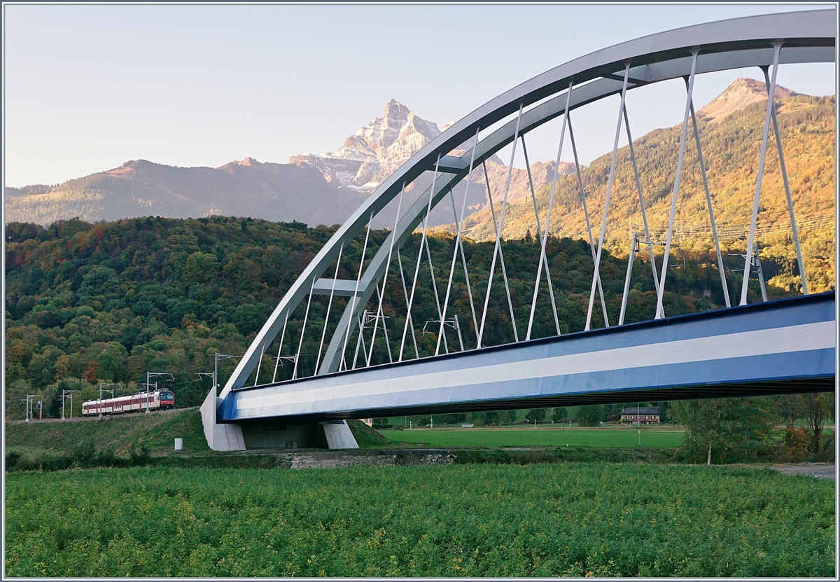 Fast 23 Meter über die Gleise wölben sich die beiden Bögen der SBB Brücke  Massongex , die zwischen Bex und St-Maurice über die Rhone führt. Die Brücke weist eine Spannweite von 125.8 Meter auf und gilt als längste Stählerne Eisenbahnbrücke der Schweiz. Sie ersetzt seit 2016 die beiden aus den Jahren 1903 und 1924 stammenden eingeleisigen Stahlbrücken. (Tech. Ang. Quelle: TEC21 Nr 41). 
im Hintergrud ein  Waliser  Domino auf der Fahrt Richtung Aigle. 
11. Okt. 2017