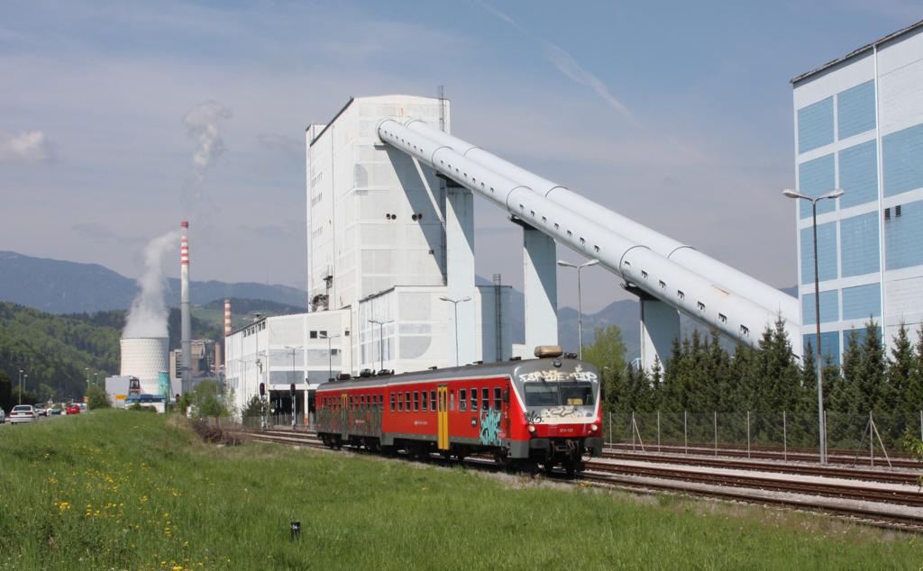 Fast verloren wirkt der Triebwagen 814122 vor der Kulisse des Kraftwerks in Velenje. Die Aufnahme entstand am 28.4.2012 bei der Einfahrt des Zuges in den unmittelbar am Kraftwerk gelegenen Bahnhof.