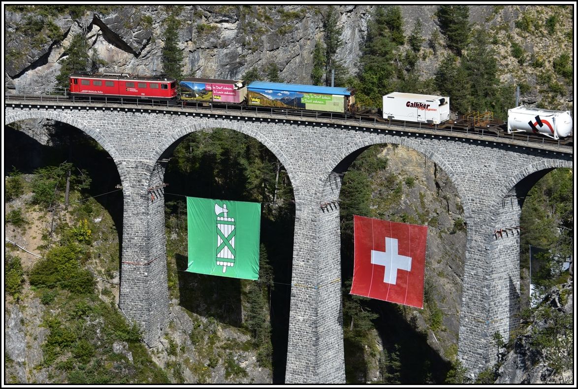 Fast wie eine Modelleisenbahn wirkt der Güterzug mit der Ge 6/6 II 705  Pontresina/Puntraschigna  auf dem Landwasserviadukt. Im September war der Kanton St.Gallen Gastkanton, weshalb dessen Flagge die Brücke ziert. (30.09.2019)
