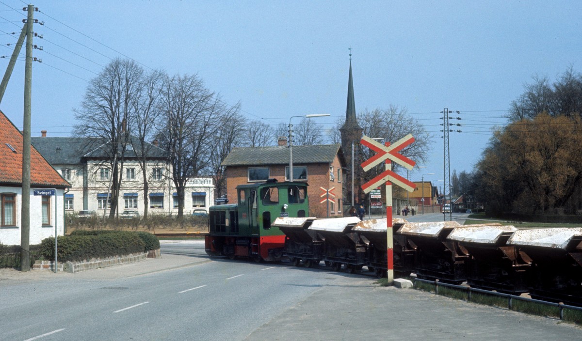 Faxe Jernbane: Kalkgüterzug (Schöma-Diesellok mit Kipploren) Fakse Ladeplads am 24. April 1973. Der Zug befindet sich auf dem Verbindungsgleis zwischen dem Bahnhof (links) und dem Hafen (rechts). Seit 1982 fahren die Kalkzüge nicht mehr.