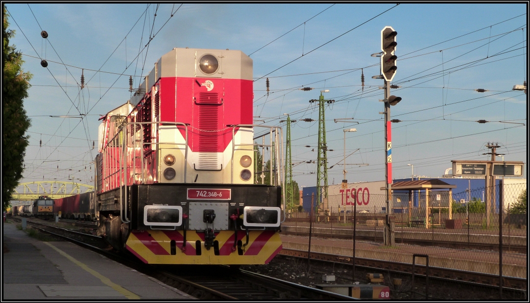 Foto Nr.1300 ist im Kasten. Es zeigt die slowakische 742 348-6 der Loko Rail A.G. mit einen langen Containerzug am Haken bei der Ausfahrt am Bahnhof von Komárom (H)  rüber nach Komárno(SK) Anfang August 2015.