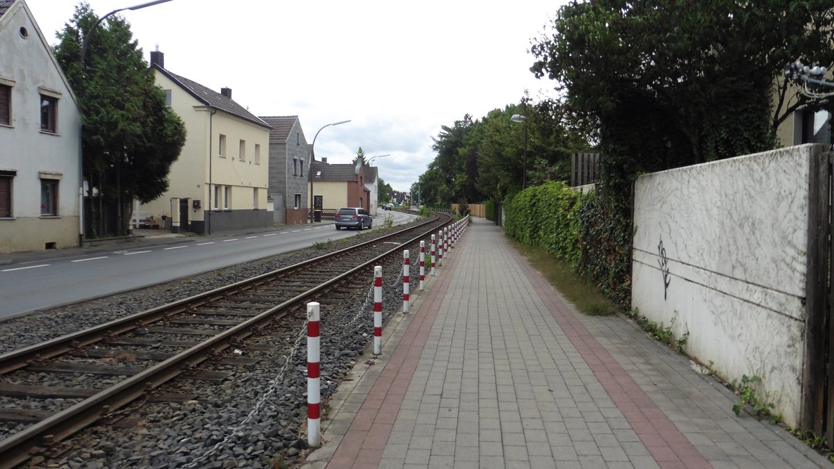 Fotos einer Privatstrecke.                                                      #2
Die Evonik-Bahn von Troisdorf nach Niederkassel wurde zwichen 1906 und 1914 gebaut, damals war die Strecke 34,4 km Lang, heute sind es 15,3 km. Von 1914 bis in die 1960er Jahre fuhr neben Güterverkehr auch Personenverkehr, der leider Abschnitteweise aufgelöst wurde. Im Jahr 1966 wurde aufgrund des fehlenden PV der GV auf Dieselloks umgestellt, der bis heute anhält. In den Jahren zwichen 1970 bis 1980 wurde der Verkehr aufgrund der Vergrößerung der Kreises von der Rhein-Sieg-Kreis Eisenbahn und der Rhein-Sieg-Verkehrsgesellschaft zusammengeführt. Nachdem sich die RSE von der Strecke abgewand hat, übernamm die RSVG denn Verkehr. Dieser war mal 3 Zugpaare am Tag, heute ist es 1 einziger Zug der am Tag fährt. Die Betriebsgenehmigung für die Strecke wurde am 15. Februar 1984 bis zum 30. September 2021 verlängert. Allerdings könnte in Naher Zukunft eine Stadtbahn mit auf der Evonik-Bahn fahren, ob es das Stadtbahnnetz von Köln oder Bonn kommt ist noch nicht geklärt. 

Hier in Troisdorf Sieglar machte Ich die Aufnahme von der Bahn, die dierekt neben der Straße verläuft.
 
Troisdorf-Sieglar 27.07.2017 

PS: Die Strecke wird auch Rhabarberschlitten genannt.