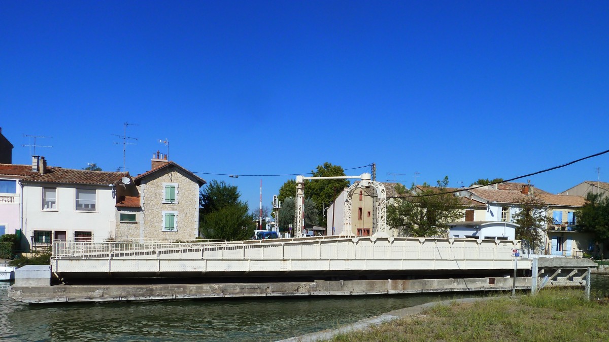 Frankreich, Languedoc, Gard, Aigues-Mortes. Die Drehbrücke über den Kanal auf der Eisenbahnlinie (Nîmes -) Saint-Césaire - Aigues-Mortes - le Grau-du-Roi. Hier ist sie um 90 Grad gedreht um die Schiffe auf dem Canal du Rhône à Sète vorbeifahren zu lassen. 13.09.2014