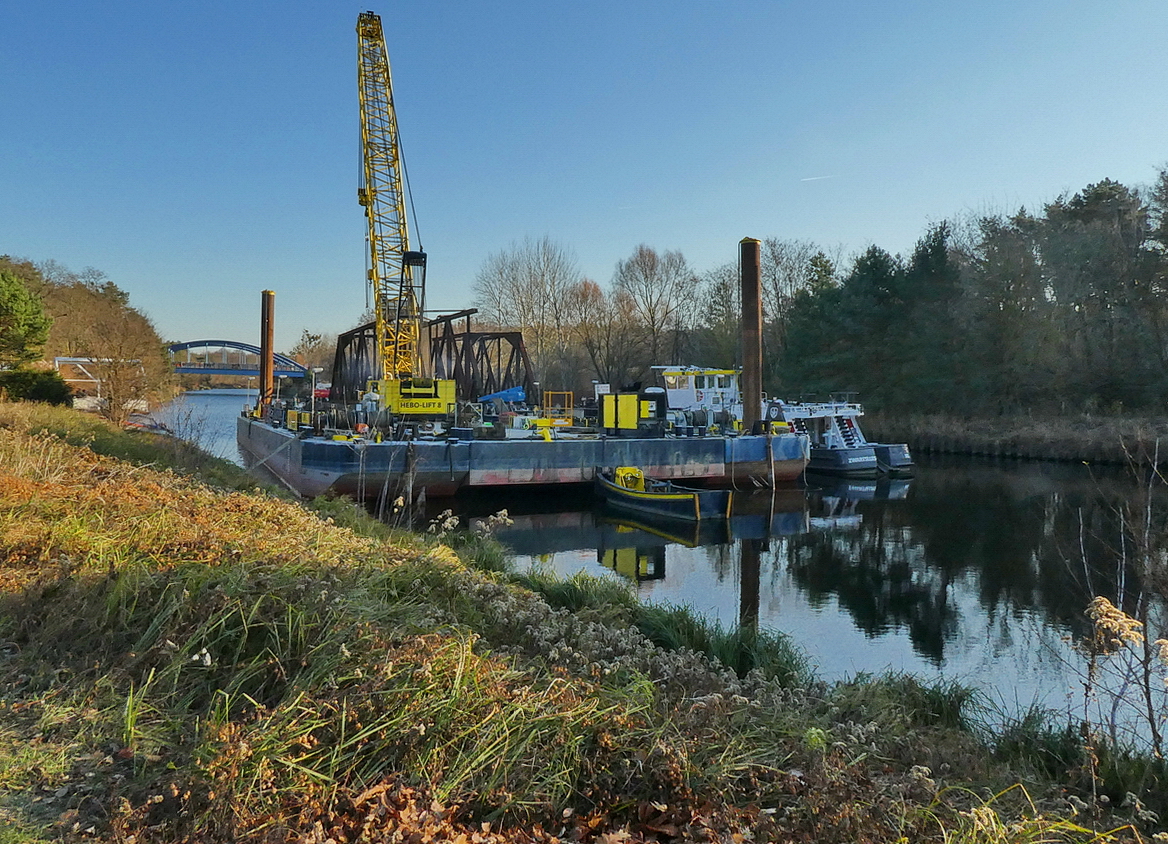  Friedhofsbahnbrücke  (ehemals den Teltowkanal überbrückend) im Vordergrund, teils zerschnitten auf einem Lastschiff. Die 105 Jahre alte Brücke verband Kleinmachnow und Stahnsdorf im Süden Berlins. Die 200 Tonnen schwere Fachwerkkonstruktion wurde 2018 abgerissen. Sie war Teil einer ca.4km langen Eisenbahnverbindung von Wannsee zu einem der größten deutschen Friedhöfe in Deutschland, dem in Stahnsdorf. Foto: Herbst 2018 