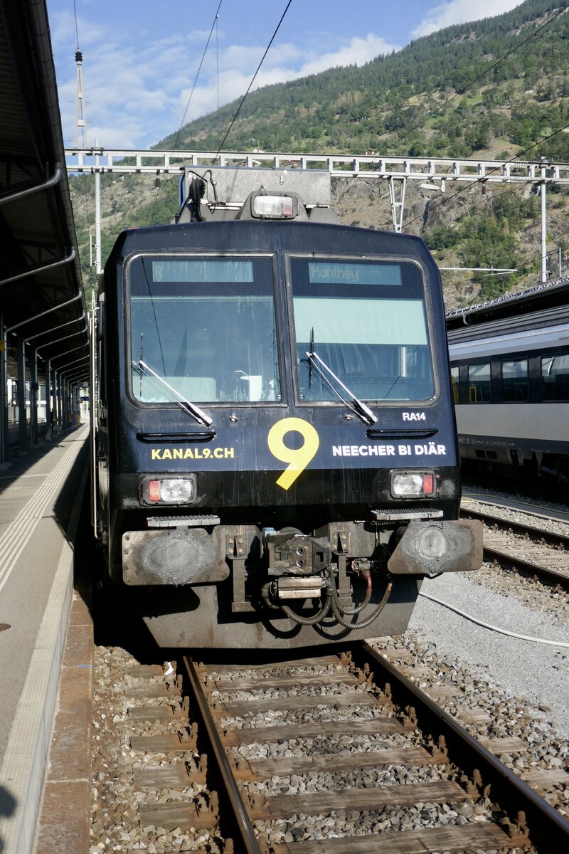 Frontansicht des Domino RA14 von RegionAlps mit der neuen Kanal 9 Werbung am 27.7.22 im Bahnhof Brig.