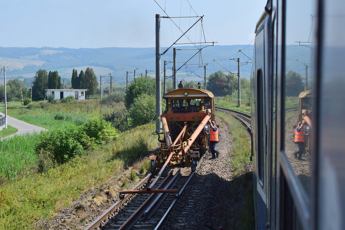 Frotnansicht auf die BNRI 85 Stopfmaschine von Matisa beim Stopfen im Gleis von Ormenis nach Apata. Der lange Vorbau dient hierbei zum Nivellieren des Gleises. Die zweite Achse des Vorbaus hält hierbei das Gleis unten während direkt unter der Stopfmaschine das Gleis leicht auf Sollage angehoben wird und unterstopft wird. 

Ormenis 02.09.2025