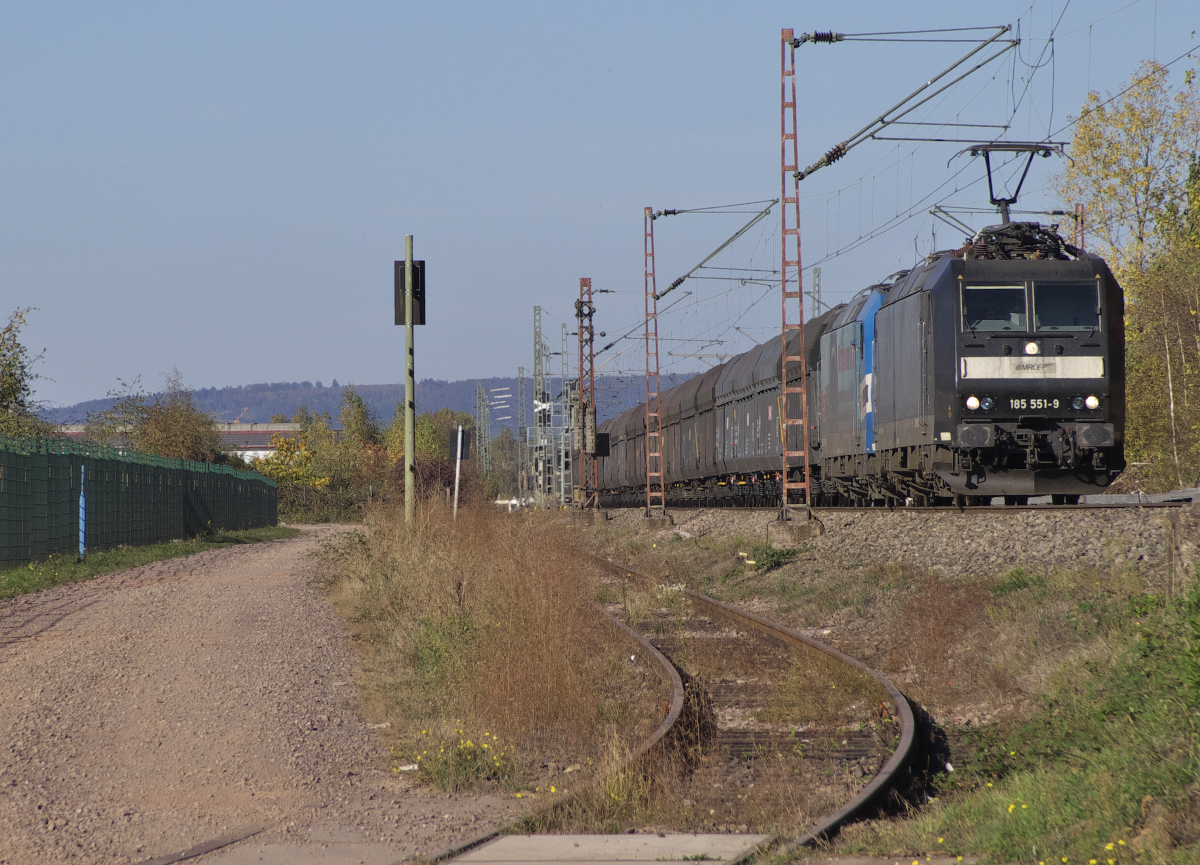 Früher betrug der Transport der Kraftwerkskohle nur wenige Kilometer, heute sind es meist mehrer tausend Kilometer. 185 551 bringt Importkohle von Rheinhafen in Duisburg zum Kraftwerk Fenne nach Fürstenhausen und passiert hier das stillgelegte Kraftwerk Ensdorf Saar. Im Schlepp läuft 185 512 mit. Diese von der CFL gemietete Lok wirbt auf ihren Seitenflächen für Lokführernachwuchs.  Wir beißen nicht  wir suchen nur Dich  so verspricht der Spruch aus dem Haifischmaul. 21.10.2018