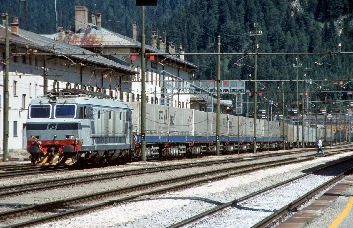 FS-Trenitalia E.652 123 mit einem Roadrailerzug der BTZ (Bayerische Trailerzug Gesellschaft fr bimodalen Gterverkehr) wartet auf die Abfahrt in Richtung Bolzano/Brenner (Bahnhof Brennero/Brenner, 23.08.2001); digitalisiertes Dia. - Diese Form des Transports von Sattelaufliegern, bei dem der vordere und hintere Teil auf je einem speziellen Drehgestell ruht, hatte sich nicht bewhrt und wurde nach einigen Jahren wieder eingestellt. Die BTZ musste in der Folge Insolvenz anmelden.



