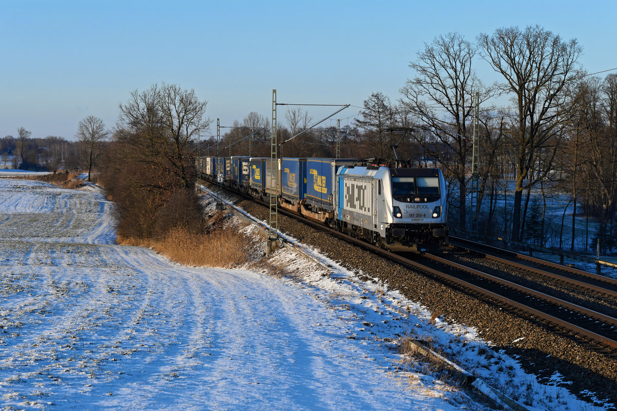 Für Lokomotion ist aktuell die 187 310 von Railpool im Einsatz. Am frostigen 11. Februar 2021 stand die Sonne schon tief, als sie die ehemalige Blockstelle Hilperting mit dem DGS 43115 nach Verona Q.E. passierte. 