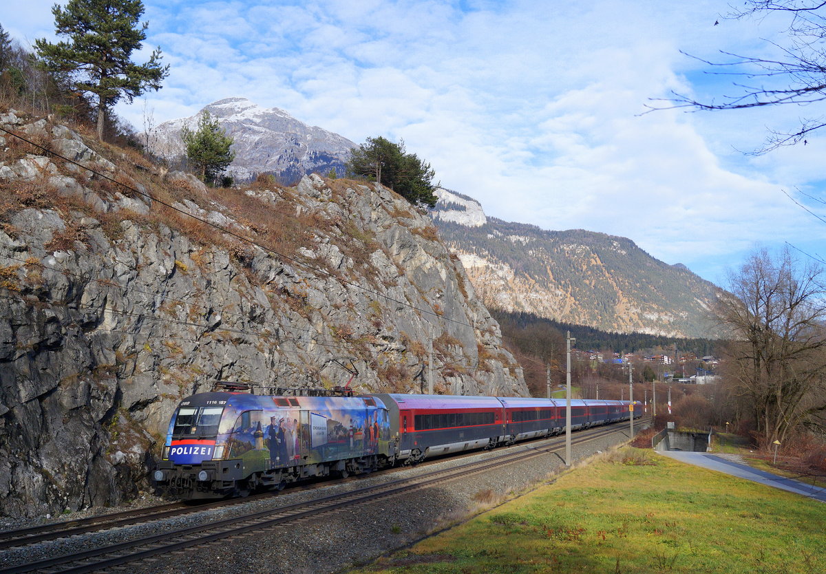 Für den RJ 662  Achensee  von Flughafen Wien nach Bregenz war an Mariä Empfängnis 2018 die 1116 157  Gemeinsam sicher mit den ÖBB  eingeteilt. Hier zieht sie ihre saubere Railjet-Garnitur pünktlich an der Jenbacher Steinwand vorbei, um in Kürze am dortigen Bahnhof zu halten. 08.12.2018.
