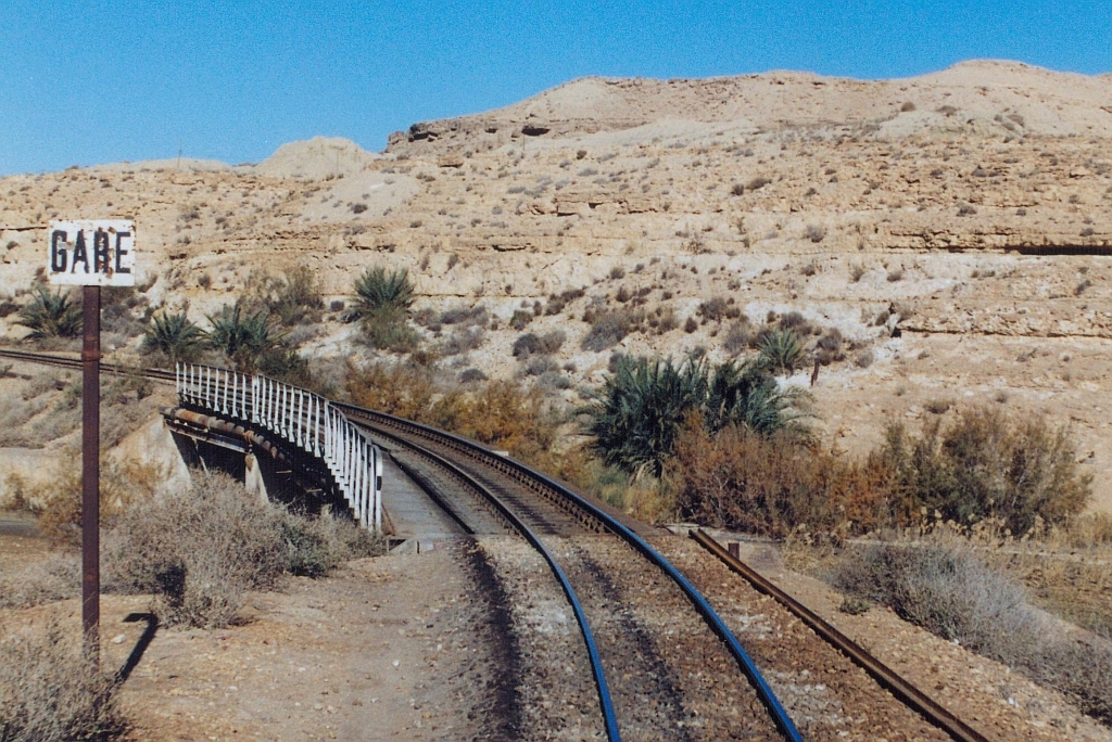 Für den Streckenabschnitt von Metlaoui nach Selja durch das Oued Thelja wurden sieben Tunnels benötigt. Gleich nach verlassen des siebenten Tunnel kündigt diese Tafel den Gare de Selja an, welcher sich nach der Brücke auf der anderen Talseite befindet. Bild vom 29.Dezember 2001. (Fotoscan)