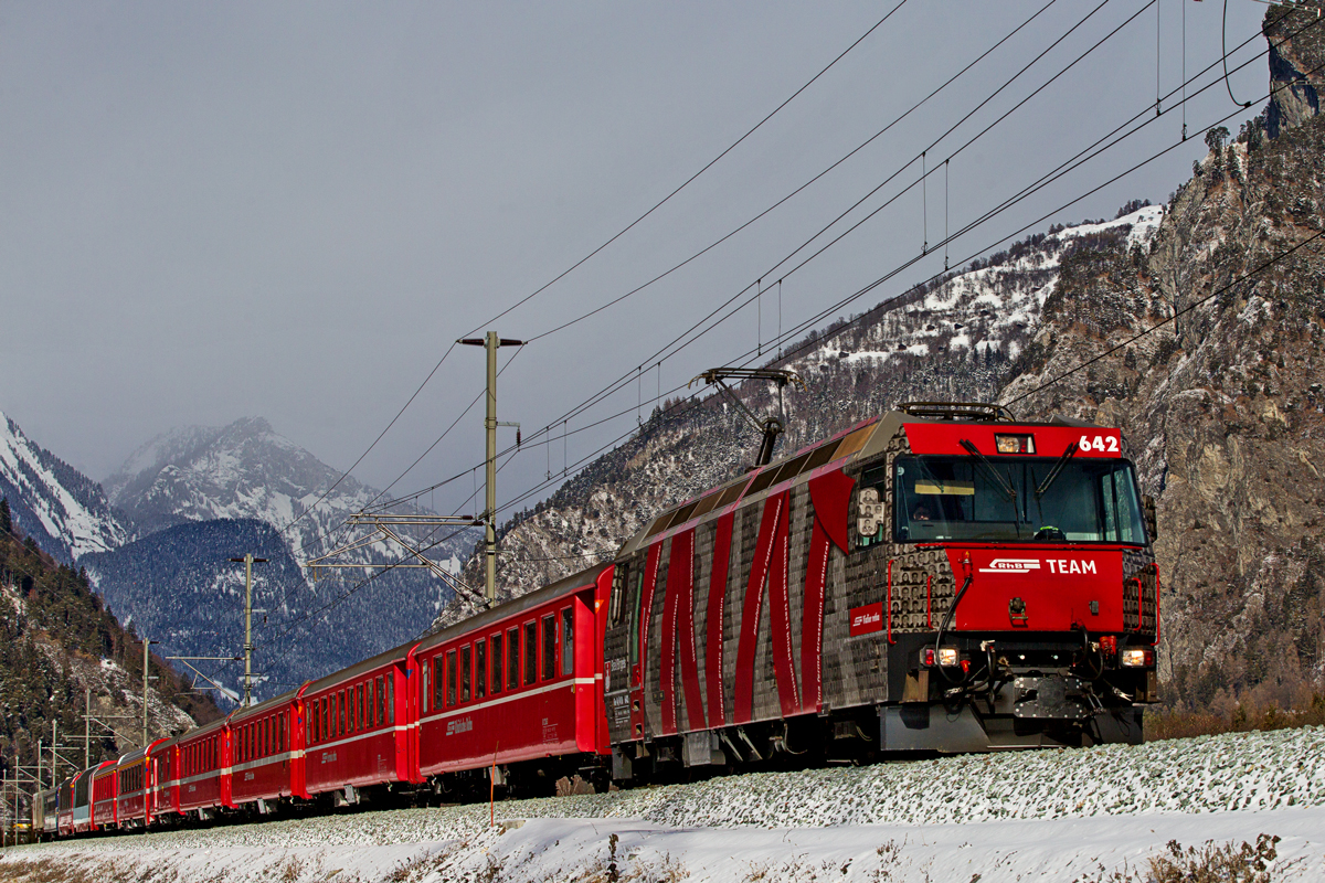 Ge 4/4 III 642 fährt Bei Realta mit einem Re von Chur nach St.Moritz mit einem wahren Sammelsurium an Wagentypen vorüber.Bild vom 19.1.2016