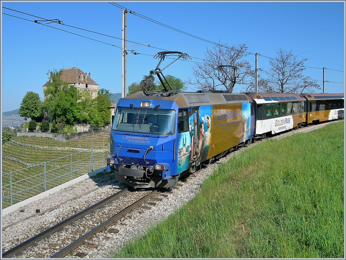 Ge 4/4 (Serie 8000) mit dem Goldenpass Panoramic 2119 von Zweisimmen nach Montreux kurz vor dem Ziel bei Châtelard VD. 
Auf dem Hügel thront, von Bäumen versteckt, das Château de Châtelard. 
22. April 2007