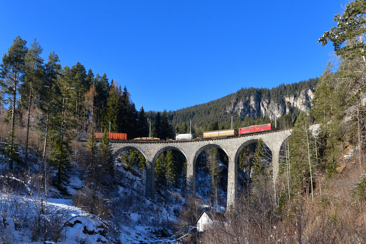Ge 6/6 II 703 mit einem Güterzug am 06.12.2017 am Schmittentobelviadukt bei Filisur. 