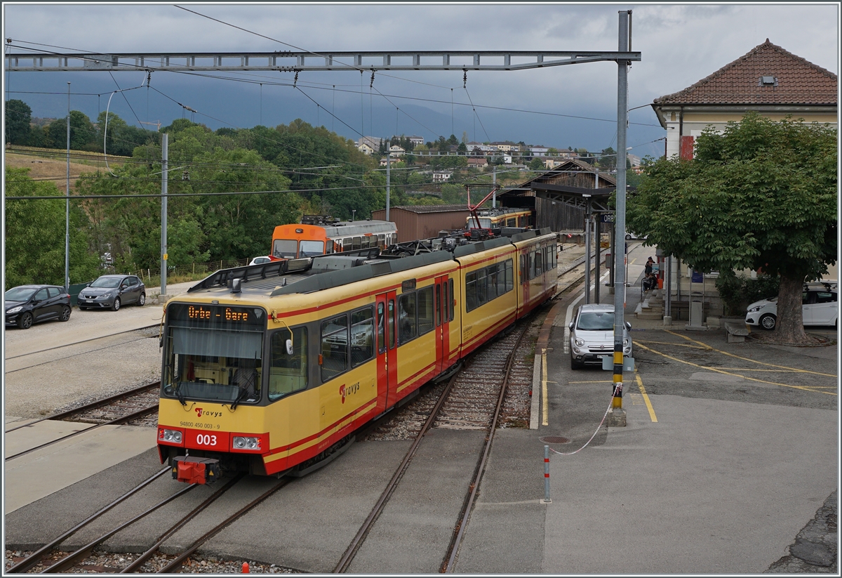 Gelbe Züge: Bis zur Realisierung der Stromsystemumstellung und besonders der Umbauarbeiten in Chavonray sind bei der TRAVYS / OC zwei Be 4/8 (GT8-100D/2S) im Einsatz. Das Bild zeigt den aus Chavornay in Orbe ankommenden Be 4/8 003 (94 80 0450 003-9). Im Hintergrund der auf einen neuen Stromabnehmer wartende Be 4/8 004. 

15. August 2022