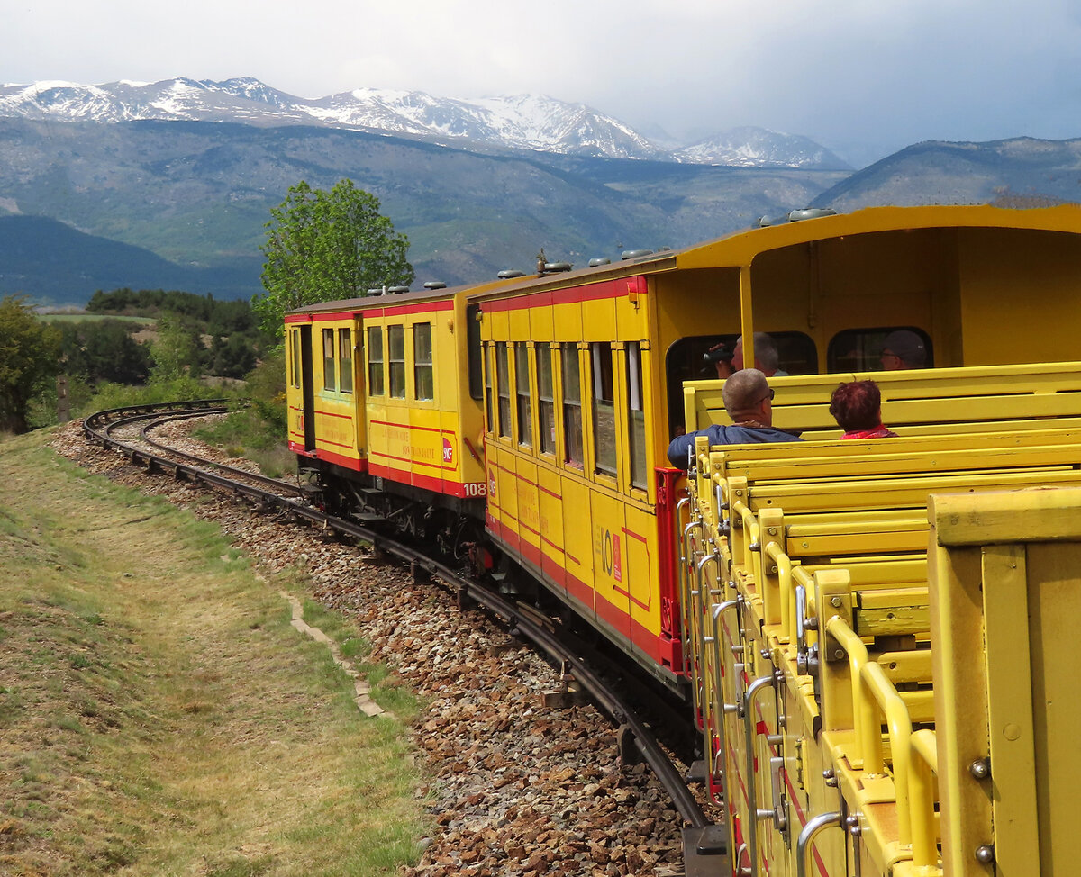 Gemütliche Fahrt an der frischen Bergluft vor den schneebedeckten Bergen. Gut ersichtlich ist hier die seitliche Stromschiene links vom Gleis. Latour-de-Carol, 24.5.2023