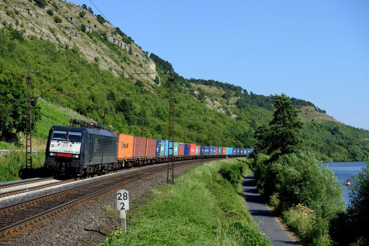 Gleich im Block dahinter kam die nächste schwarze ES 64 F4 am Main entlang gefahren. Welche Leistung die ES 64 F4 159 von MRCE dispolok am Haken hatte, konnte leider nicht in Erfahrung gebracht werden, die bunten Container hoben sich jedenfalls schön ab (20. Juli 2013 bei Gambach).