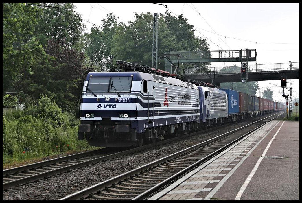 Gleich zwei moderne Elektroloks kommen hier am 4.6.2021 um 8.52 Uhr mit einem langen Containerzug in Richtung Münster durch den Bahnhof Hasbergen. Vorn zieht die VTG E 189-211. Dahinter ist 189099-5 ebenfalls am Fahrdraht.