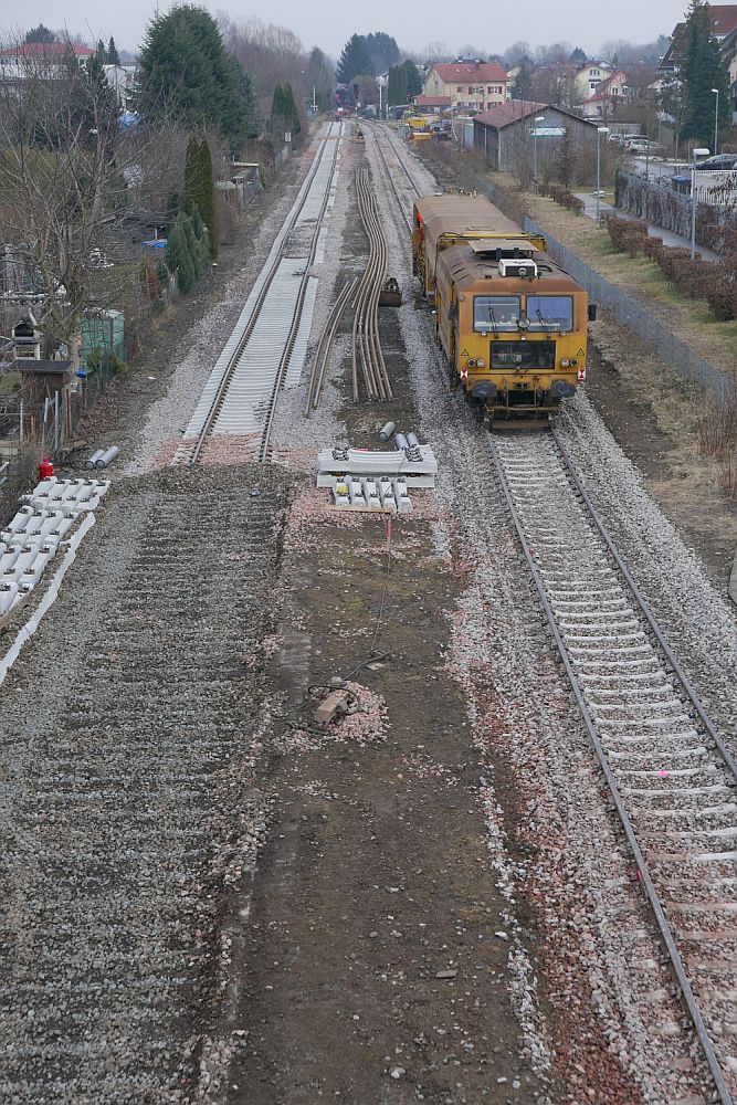 Gleiserneuerung im Bahnhof von Langenargen (|||) - Auf dem bereits vollständig erneuerten Gleis arbeitet eine Universalstopfmaschine. Blick von der Fußgängerbrücke in Richtung Lindau am 03.03.2018.
