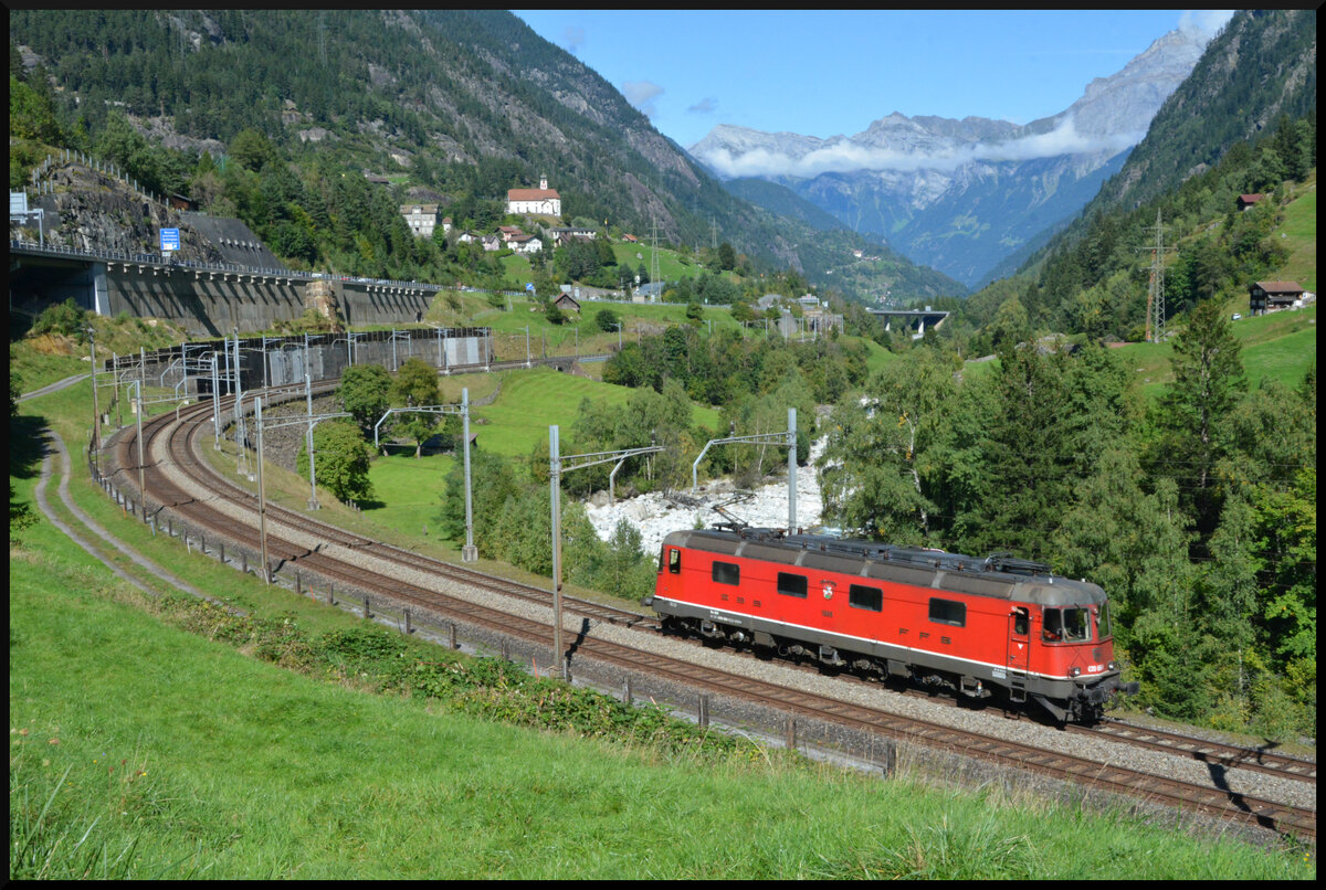 GOTTHARD-BAHNTAGE 2025: Für die Talfahrt des Dampfzuges benötigte man eine Bremslokomotive, welche in Form der Re 6/6 11666 (Re 620 066-1) dem Extrazug bei der Bergfahrt solo folgte. Die sechsachsige Lokomotive ist mit ETCS ausgestattet und ein Neuzugang bei SBB Historic in Erstfeld. Hier befindet sich die Maschine am 14.09.2025 unterhalb der berühmten Kirche von Wassen in der Wattinger Kurve.