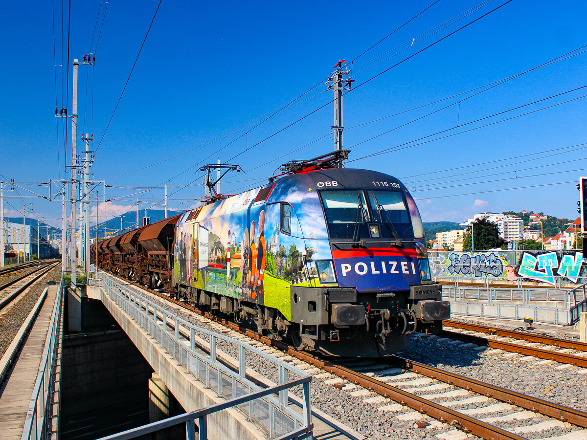 Graz. Die Polizei-Lok 1116 157 rast hier am 22.08.2023 durch Graz-Don Bosco.