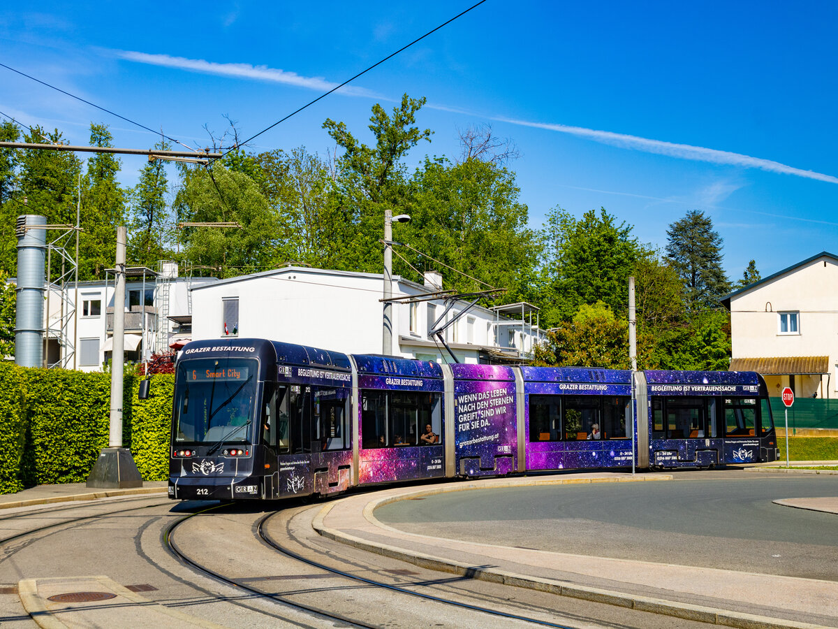 Graz. Variobahn 212 der Graz Linien, in ihrer bunten Bestattungs-Werbung, ist hier am 29.04.2024 bei der Einfahrt in die Endschleife St. Peter zu sehen.