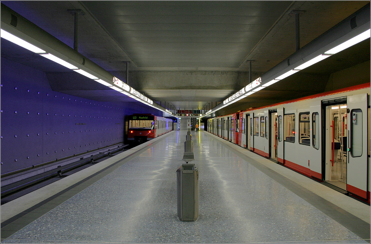 Gustav-Adolf-Straße - 

Blick in den vorläufigen Endbahnhof der Linie U3 im Südwesten Nürnbergs. Dieser Bahnhof liegt in eineinhalbfacher Tieflage. Die Streckentunnel des U3-Abzweiges wurden bergmännisch in Einzelröhren erstellt, die Bahnhöfe (erkennbar am rechtwinkeligen Querschnitt) dagegen in offener Bauweise. Die U3 soll von hier mit zwei unterirdischen Zwischenstation weiter zum oberirdischen Bahnhof Gerbersdorf verlängert werden. Langfristig soll in zwei teilweise eingleisigen Zweigstrecken Zindorf und Oberasbach erreicht werden.

28.06.2008 (M)