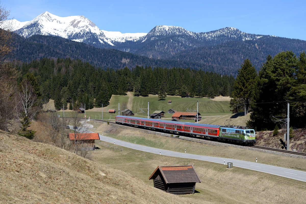 Gut eine Stunde später war es Zeit für RB 59499 nach Mittenwald, Zuglok passend ausgewählt zur Landschaft die DAV-Werbelok 111 039. Hier zu sehen in den Buckelwiesen bei Klais (14. April 2013).