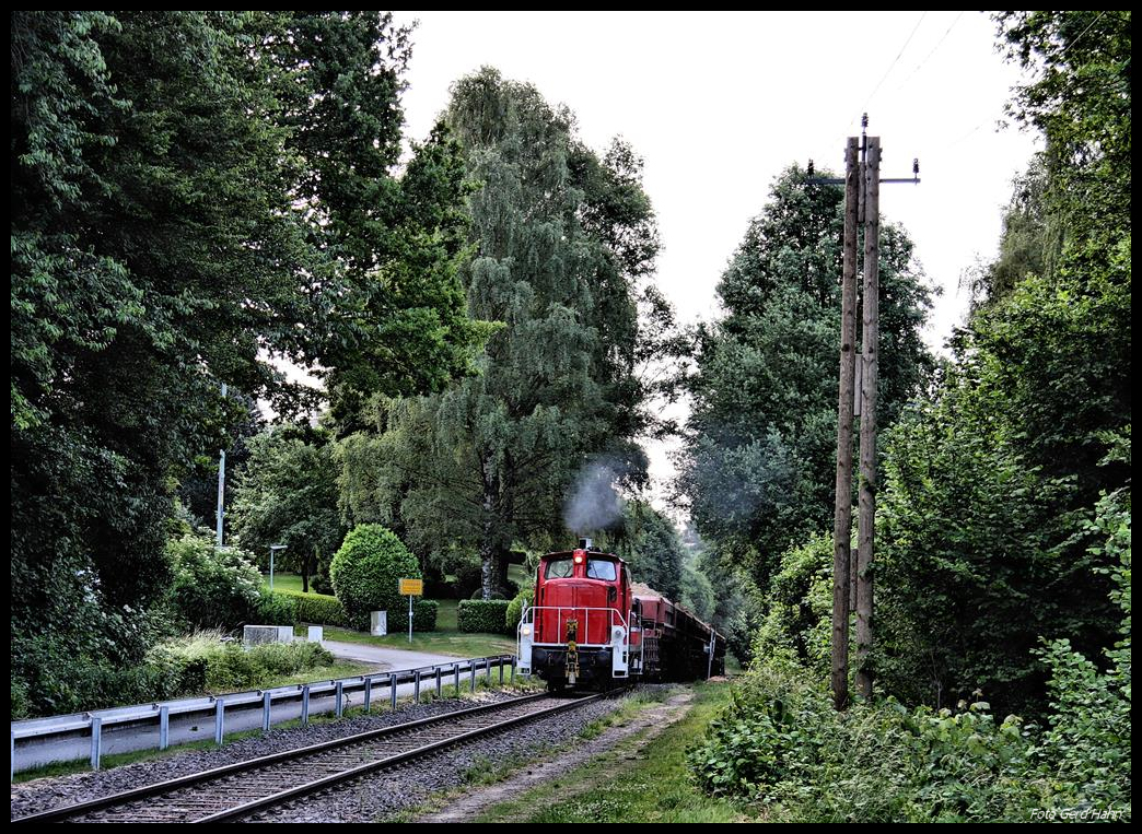 Haba 7 der Hafenbahn Osnabrück verläßt hier am 7.6.2017 morgens um 06.00 Uhr mit ihrem Schuttzug gerade den Einschnitt am ehemaligen Bahnhof Patkenhof. Sie ist auf dem Weg zur Entladestelle am Augustaschacht. Deutlich ist in Höhe des Ortseingangsschildes von Holzhausen der Scheitelpunkt der Strecke zu erkennen.