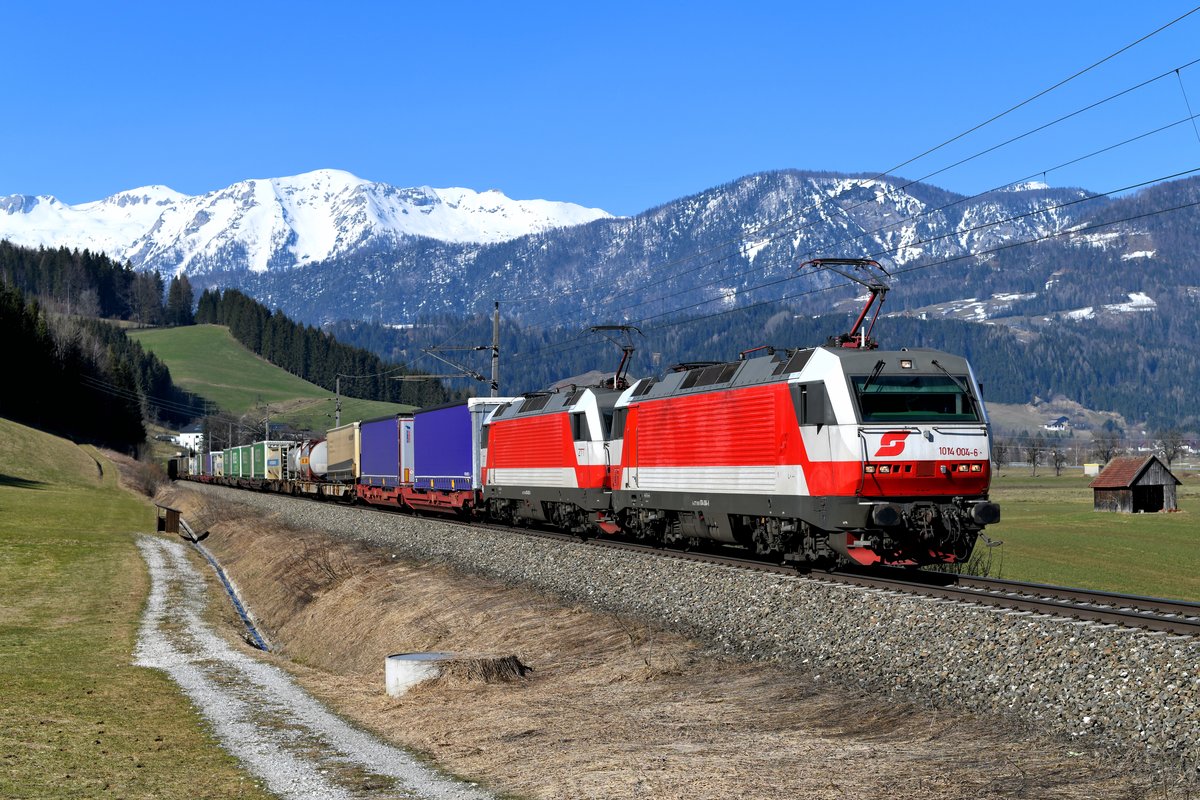 Hätte mir jemand vor einem Jahr gesagt, dass ich nochmal die Möglichkeit haben würde, Loks der Baureihe 1014 im Planeinsatz zu fotografieren, dann hätte ich dieser Person Realitätsverlust vorgeworfen. Aber bei der Bahn gibt es nichts, was es nicht gibt. Aus Fotografen-Sicht kommt es dabei auch zu ganz erfreulichen Entwicklungen. So zum Beispiel bei einer meiner Lieblingsbaureihen, der formschönen, aber im damaligen Planeinsatz eher glücklosen Mehrsystemlok 1014. Seit 2009 aus regulären Umläufen verschwunden und in 2016 zur Verschrottung nach Rumänien abgefahren, hatte die Firma Zeller Transporttechnik im Vorjahr fast den kompletten Bestand wieder nach Österreich zurückgeholt und einige Maschinen wieder betriebsfähig hergerichtet. Eingesetzt werden die Loks im klassischen Design der 1990-er Jahre hauptsächlich vor dem sogenannten Wenzel-KLV zwischen Wels und Katsdorf. Dieser Zug verkehrte an Sonntagen bei Tageslicht, sonst stets in der Nacht. Inzwischen wird allerdings generell Nachts gefahren. Der Zug zog naturgemäß die Eisenbahnfreunde in den Bann und war die letzten Wochen ein begehrtes Fotomotiv. Am 24. März 2019 war es mir bei herrlichem Frühlingswetter vergönnt, die 1014.004 und 003 vor dem komplett beladenen SETC 96816 zwischen Windischgarsten und Spital am Pyhrn aufzunehmen.