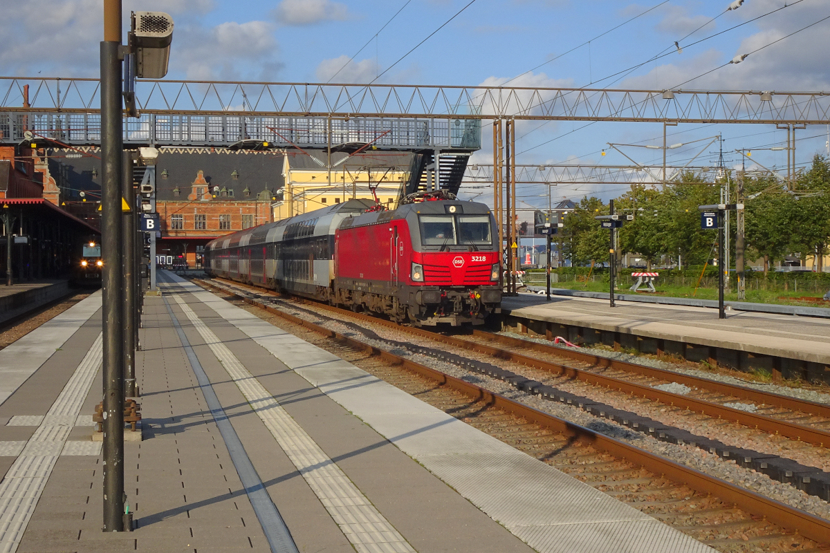 Helsingør an einem Samstagabend: Vectron EB 3218 der DSB steht mit einem Doppelstockzug zur Fahrt durch Kopenhagen nach Roskilde bereit. Ganz am linken Bildrand erkennt man einen der komfortablen Elektrotriebzüge der Reihe ET der DSB.
Helsingør, 2. September 2023, 18.07 Uhr (Kamera zeigt Winterzeit.....)