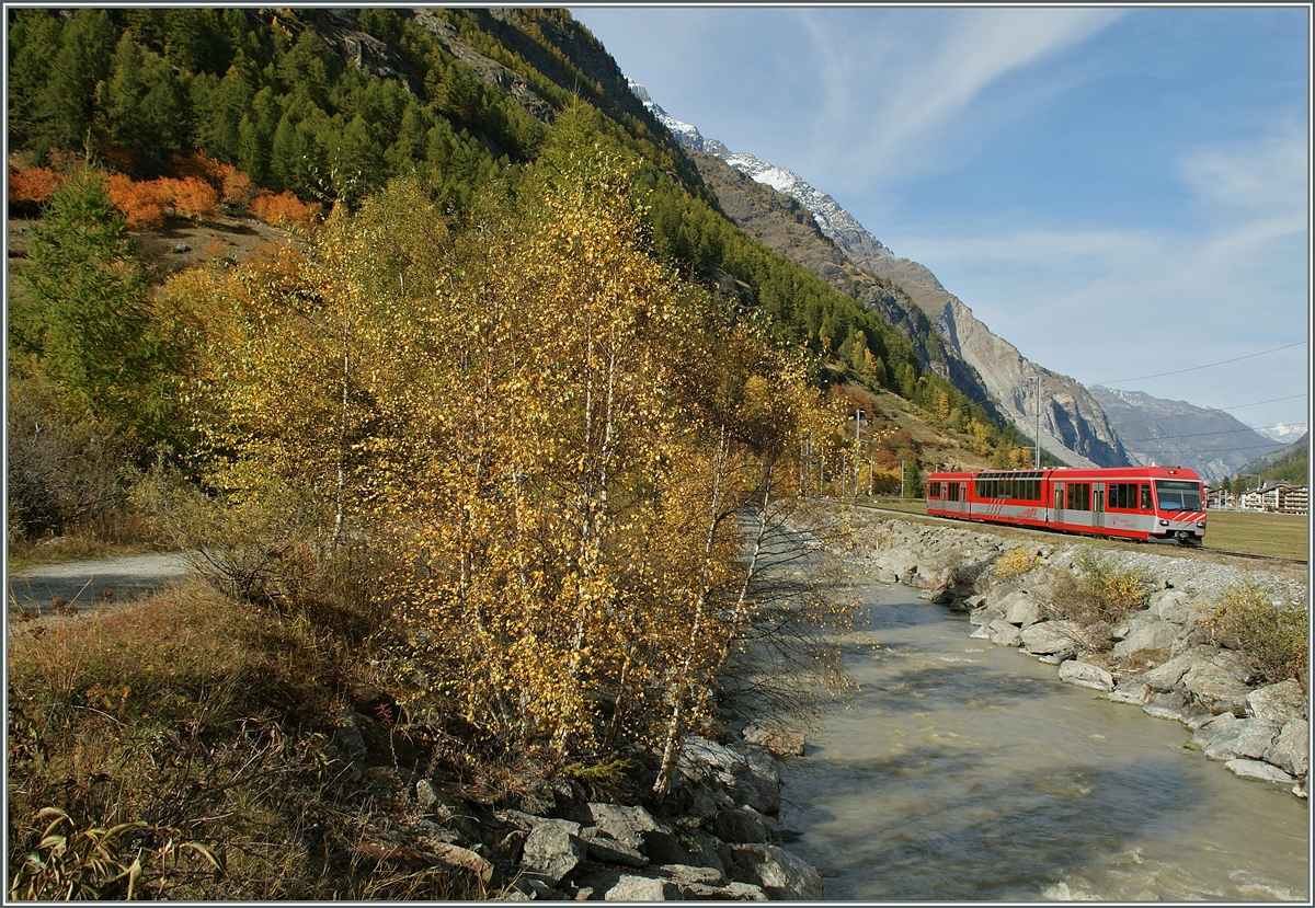 Herbst im Mattertal, durch welches ein der  rot/graue  Zermatt Shuttle Richtung Zermatt fährt. 
21. Okt. 2013